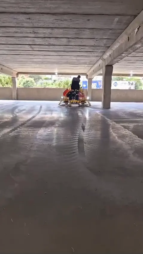 Acabadora de piso em operação sobre concreto fresco em galpão, obra de piso industrial da AMC Engenharia